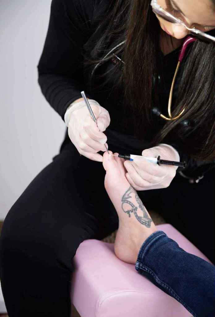 Jessie in gloves performing precise toenail care on a patient’s foot